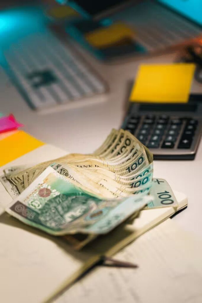Close-up of Polish Zloty banknotes on a desk with a calculator and sticky notes, emphasizing finance and budget planning.